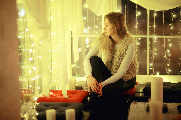 dívka u okna sní o snech v zimě večer, o romantice svíce, o nádherném modelu vánočních snů - Fotografie, Obrázek