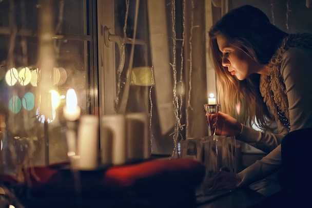 girl at the window dreams in winter evening / the romance of candle, the beautiful model in Christmas evening dreams - Valokuva, kuva