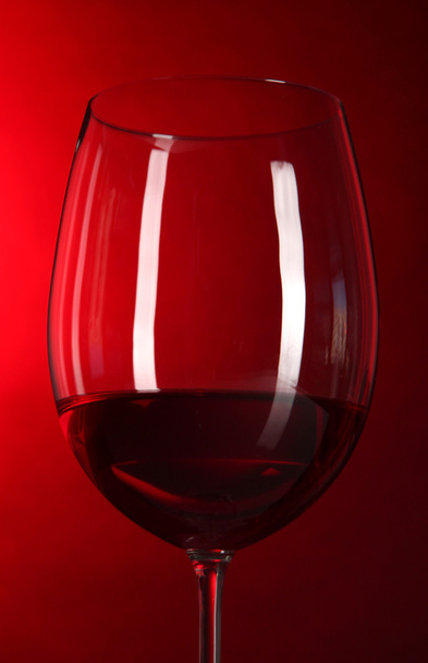 Glass of wine on bright red background - Фото, изображение