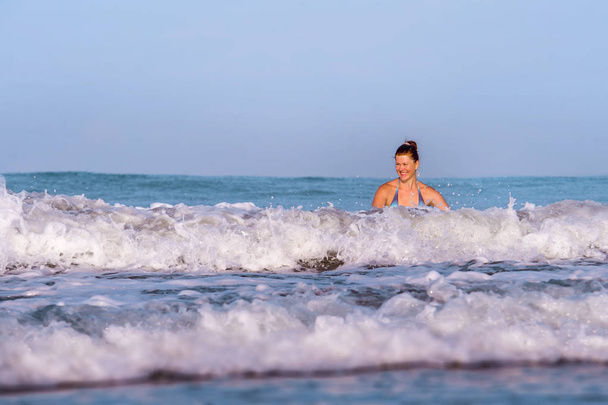 fiatal boldog és játékos vörös hajú nő bikini úszás a tengeren játszik nagy hullámok élvezi nyári nyaralás paradicsom strand nyugodt és izgatott az úticél - Fotó, kép