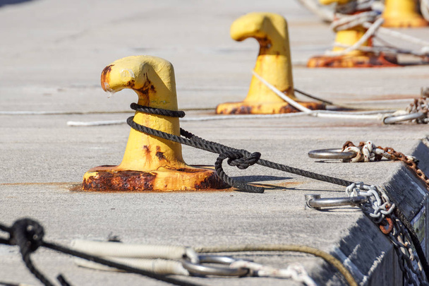 Швартовочная пуля, переплетенная швартовочной веревкой. Корабли на портовой набережной
 - Фото, изображение