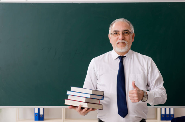 Ηλικιωμένος δάσκαλος μπροστά σε μαυροπίνακα  - Φωτογραφία, εικόνα