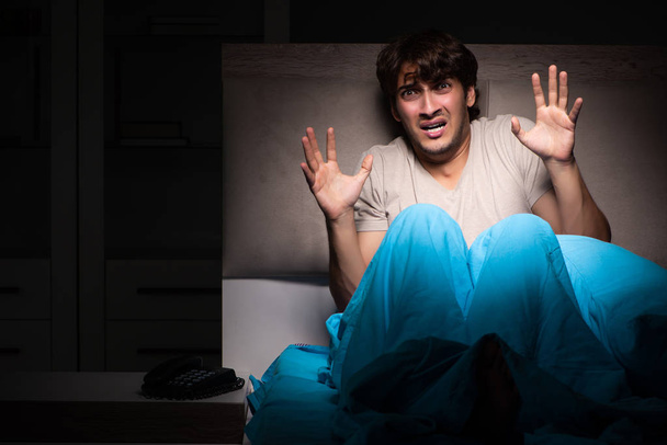 Young man scared in his bed having nightmares - Fotografie, Obrázek