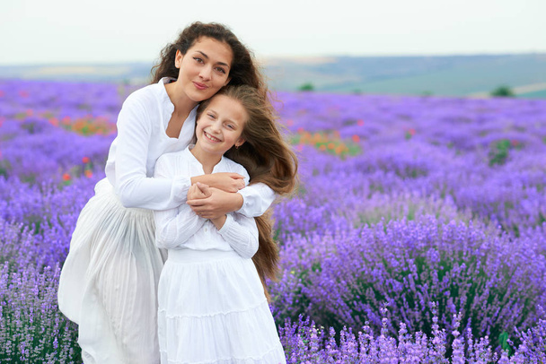 girls are in the lavender flower field, beautiful summer landscape - Foto, afbeelding