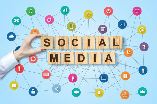 Social media concept with female hand and social icons on wooden blocks. Blue background Communication tools. - Photo, Image