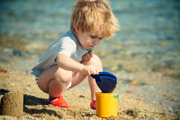 Game on the beach. A child near the sea. Healthy holidays. Tourism. The boy is played with golden sand and beach toys. Summer. - Foto, Imagem