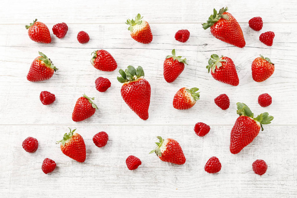 Strawberries and raspberries  on white wooden background. - Fotoğraf, Görsel