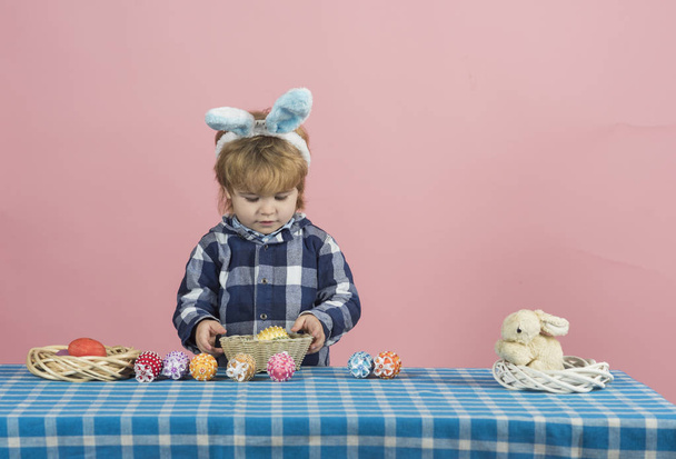 Huevos de Pascua, Niño con decoraciones de Pascua para las fiestas. Guapo chico lindo se juega con huevos de juguete antes de Pascua. Colorido festivo celebrar fondo. Niño con orejas de conejo
 - Foto, imagen