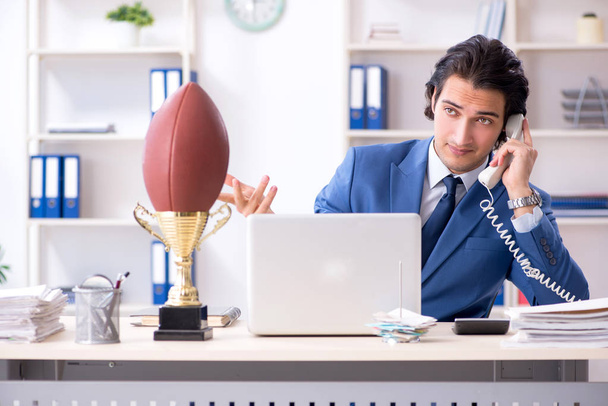 Mladý pohledný podnikatel s rugby míč v kanceláři - Fotografie, Obrázek