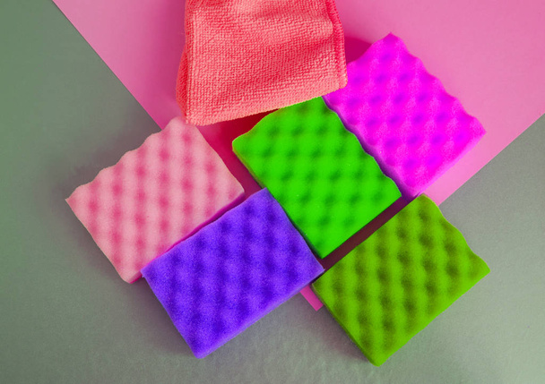 Un conjunto de esponjas multicolores y trapos para la limpieza y la limpieza sobre un fondo gris, el concepto de externalización de la empresa de limpieza, top View
 - Foto, imagen