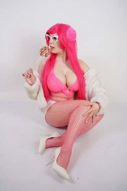 sexy chubby pink haired woman wearing sexy lingerie and fur jacket with plastic sunglasses on white studio background alone - Φωτογραφία, εικόνα