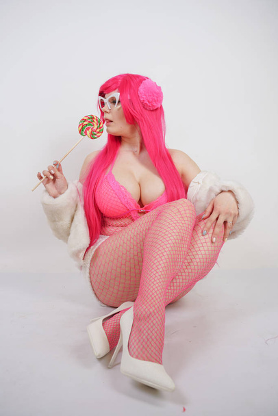 sexy chubby pink haired woman wearing sexy lingerie and fur jacket with plastic sunglasses on white studio background alone - Photo, image