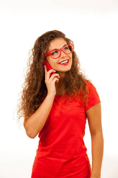 Beautiful young woman in red talking on a smart phone isolated o - Foto, Bild