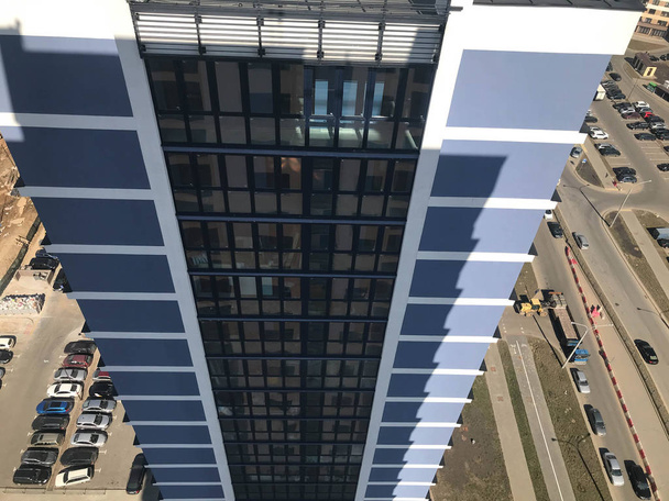 La vista desde la altura del techo de un edificio alto y grande de una casa de rascacielos en el patio con coches frente al otro edificio azul del nuevo edificio
 - Foto, imagen