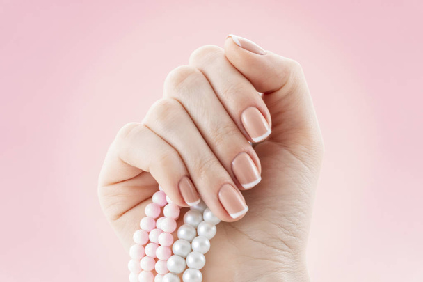 Bonito estudio de manicura francesa. Diseño natural de uñas. Mano de mujer con collar de perlas
. - Foto, Imagen