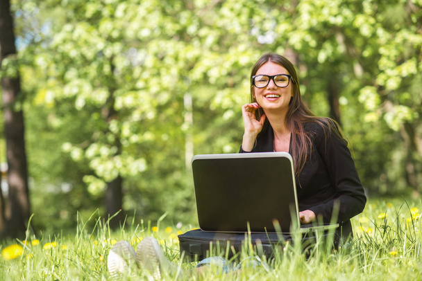 Business woman with laptop in park - Фото, изображение