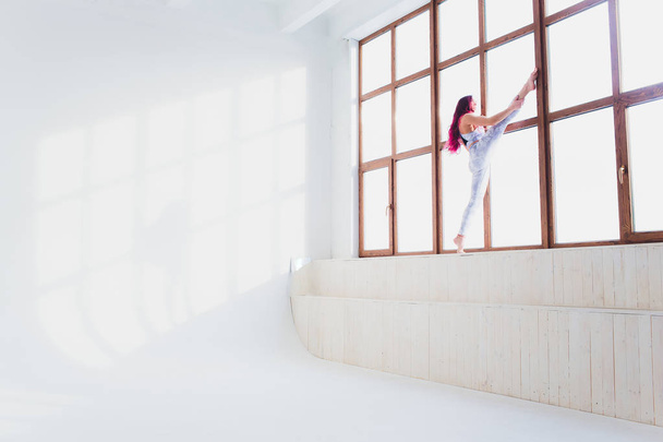 beautiful woman doing yoga and acrobatics near the big window. - Φωτογραφία, εικόνα
