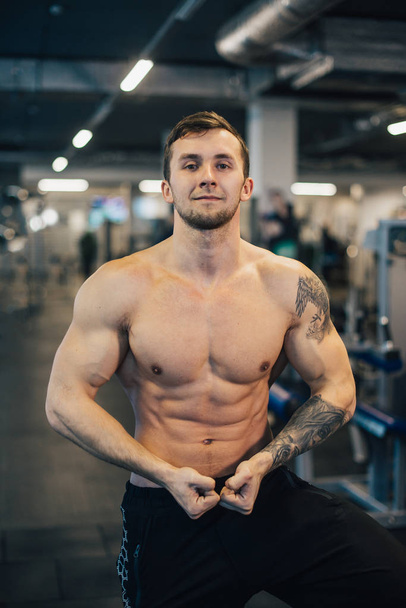 Young athletic man with naked torso standing in gym - Fotografie, Obrázek