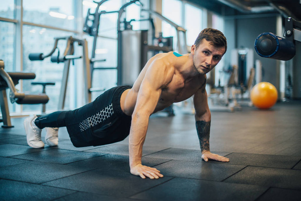 Man with naked torso wrung out from floor in gym - Fotoğraf, Görsel