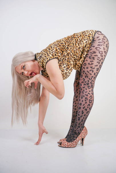 pretty plump girl wearing plush leopard print dress and transparent black pantyhose on white studio background alone - Photo, Image