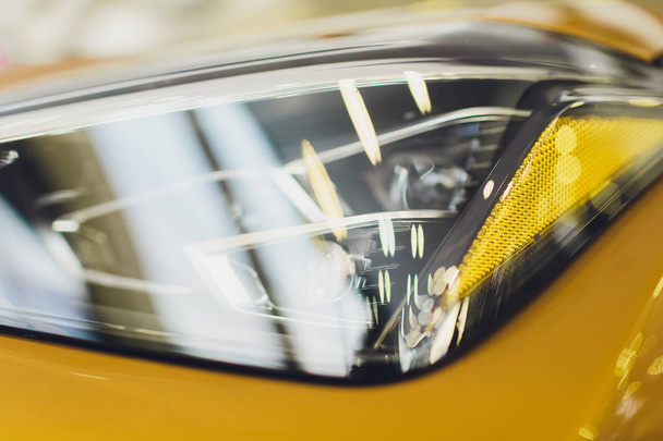Car detailing series: Clean headlights of yellow sports car. - Photo, Image