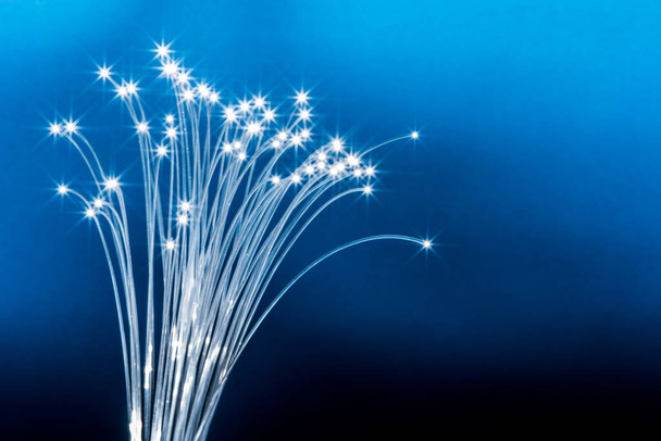 Bundle of optical fibers with lights in the ends. Blue backgroun - Fotó, kép