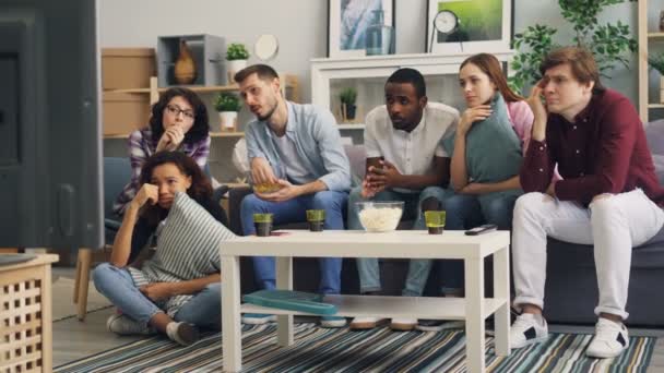 Amigos viendo triste película en la televisión llorando y comiendo bocadillos juntos en casa
 - Metraje, vídeo