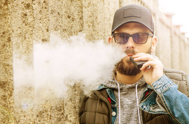 man with a beard smokes an electronic cigarette - Фото, зображення