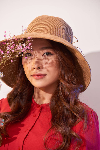 a lovely young woman in summer dress and straw hat posing while holding bouquet flowers - Foto, Imagem