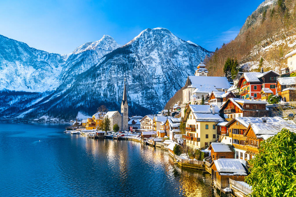 Klasická pohlednicová pohled na slavné město Hallstatt na břehu jezera v Alpách s tradiční osobní lodí za krásného studeného slunečného dne s modrou oblohou a mraky v zimě, Rakousko - Fotografie, Obrázek