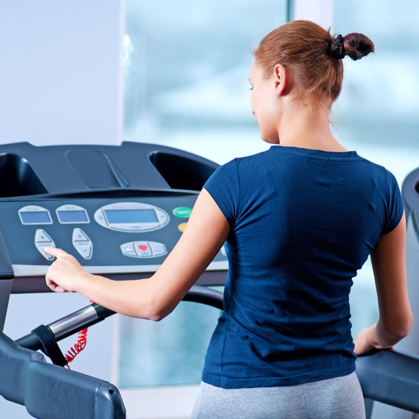 Jeune femme à la salle de gym courir sur une machine
 - Photo, image