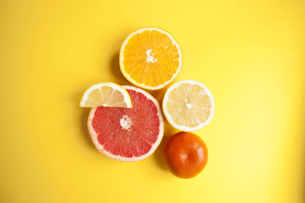 Flat lay of cut ripe juicy grapefruit, lemon and orange on yellow background. Citrus pattern. - Фото, изображение