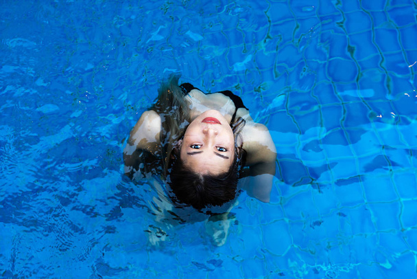 Aasialainen nainen mustissa bikineissä seisoo sinisessä uima-altaassa
 - Valokuva, kuva