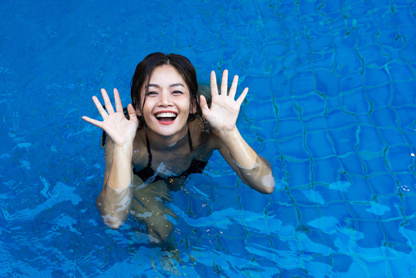 Mulher asiática jogando alegremente na piscina azul
 - Foto, Imagem