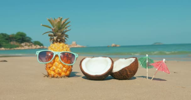 A Tropical Beach közeli gyümölcs napszemüveg a Hot Summer Sun mentén a trópusi egzotikus Coast, ananász a napszemüveg az Ocean background. Koncepció aktuális, nyár, party, Holiday. - Felvétel, videó