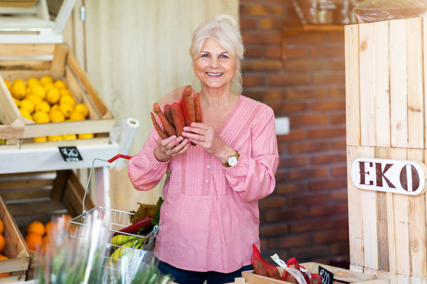 Mujer mayor trabajando en una pequeña tienda de comestibles
 - Foto, imagen
