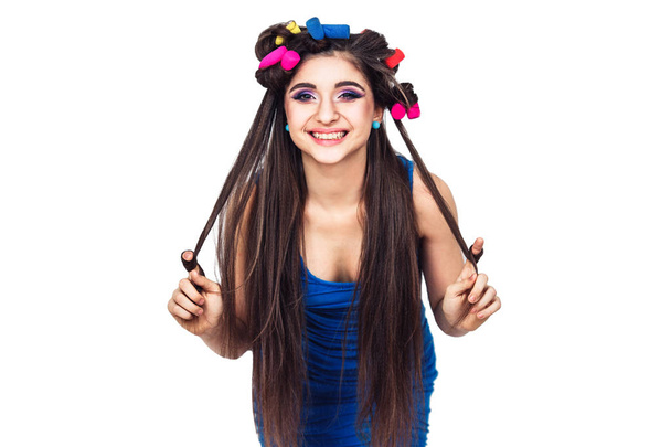 nice cheerful young girl in blue dress with curlers looks right at you. - Photo, Image