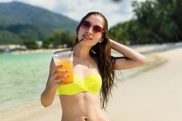 Young woman with orange juice on beach in Thailand - Fotoğraf, Görsel