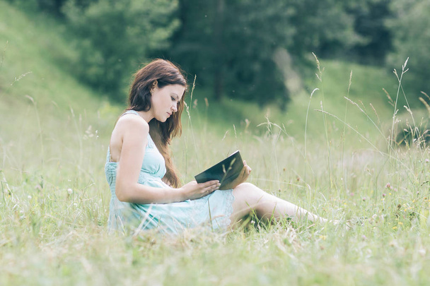 pretty young woman with a book sitting on the green grass - Φωτογραφία, εικόνα