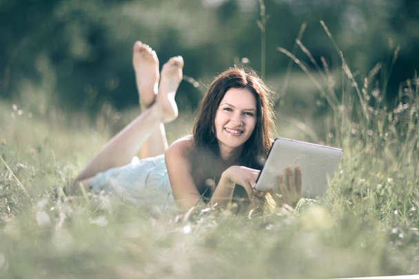 smiling young woman with digital tablet on summer meadow background. - Foto, Bild