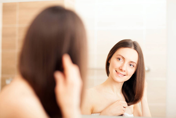 Portrait of young woman looking in mirror - Photo, Image