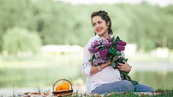 portrait of a beautiful woman with a bouquet of lilacs - Fotó, kép