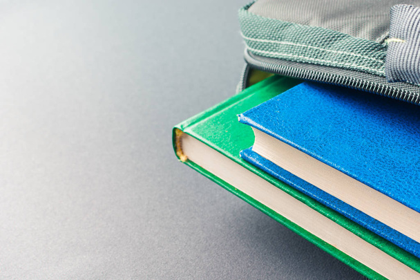 Green and blue books lie in a laptop bag - Photo, Image