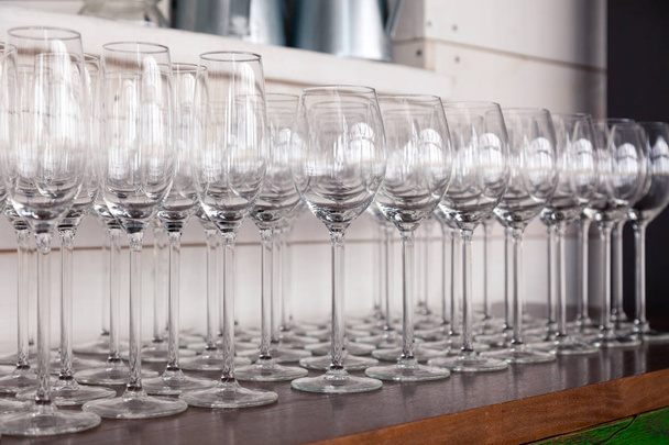 Many transparent crystal wine glasses stand in row on the brown  - Фото, изображение