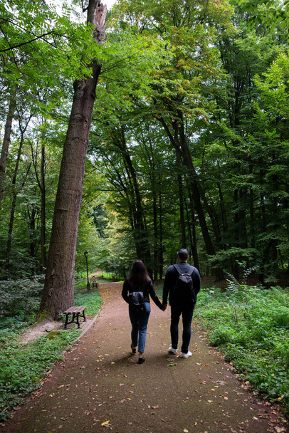 junges Paar läuft Händchen haltend durch den Stadtpark - Foto, Bild