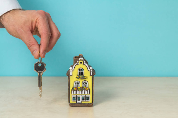 Huis model en sleutel in de hand, onroerend goed concept, turquoise kleur kopiëren ruimte.  - Foto, afbeelding