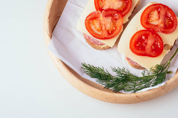 Quick cooking sandwiches with ham meat cheese tomato dill on wooden plate - 写真・画像
