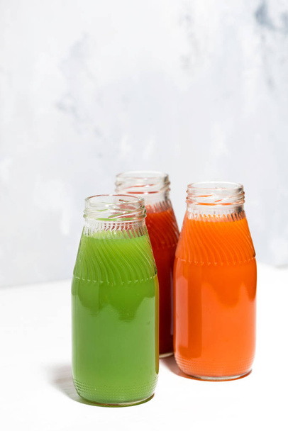 colorful vegetable juices in bottles on white background, vertic - Photo, Image