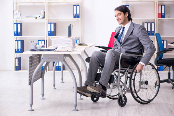 Молодий красивий працівник в інвалідному візку працює в офісі
   - Фото, зображення