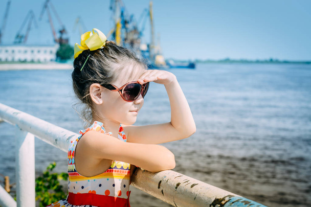 Beautiful child with glasses have a ship waiting on the pier - Fotó, kép